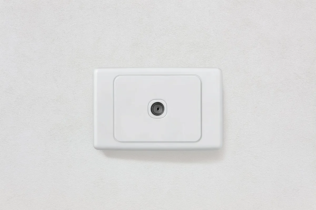 A white TV coaxial wall outlet plate mounted on a wall